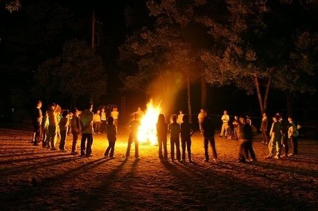キャンプファイヤーで火を囲み立っている人々