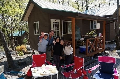 バンガローの前でキャンプを楽しむ家族