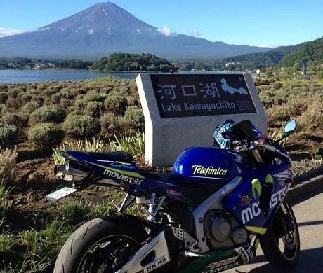 富士山を背景に河口湖の案内の前に止められているバイク