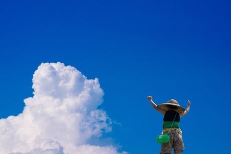 夏空で万歳をする少年