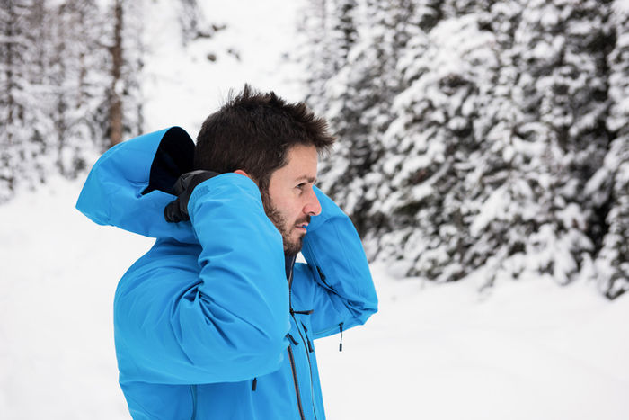 雪上でウェアのフードを被ろうとしている男性
