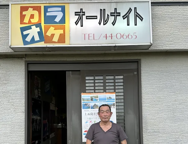 “オールナイト店前に立つ橋本さん”