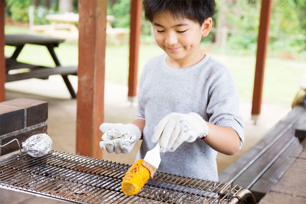 焼きとうもろこしに醤油を塗る男の子/7歳以上におすすめバーべキューお手伝い