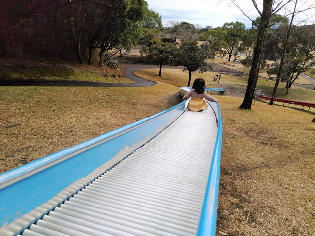 青いローラー滑り台を滑る子ども/久峰総合公園(宮崎県/宮崎市)