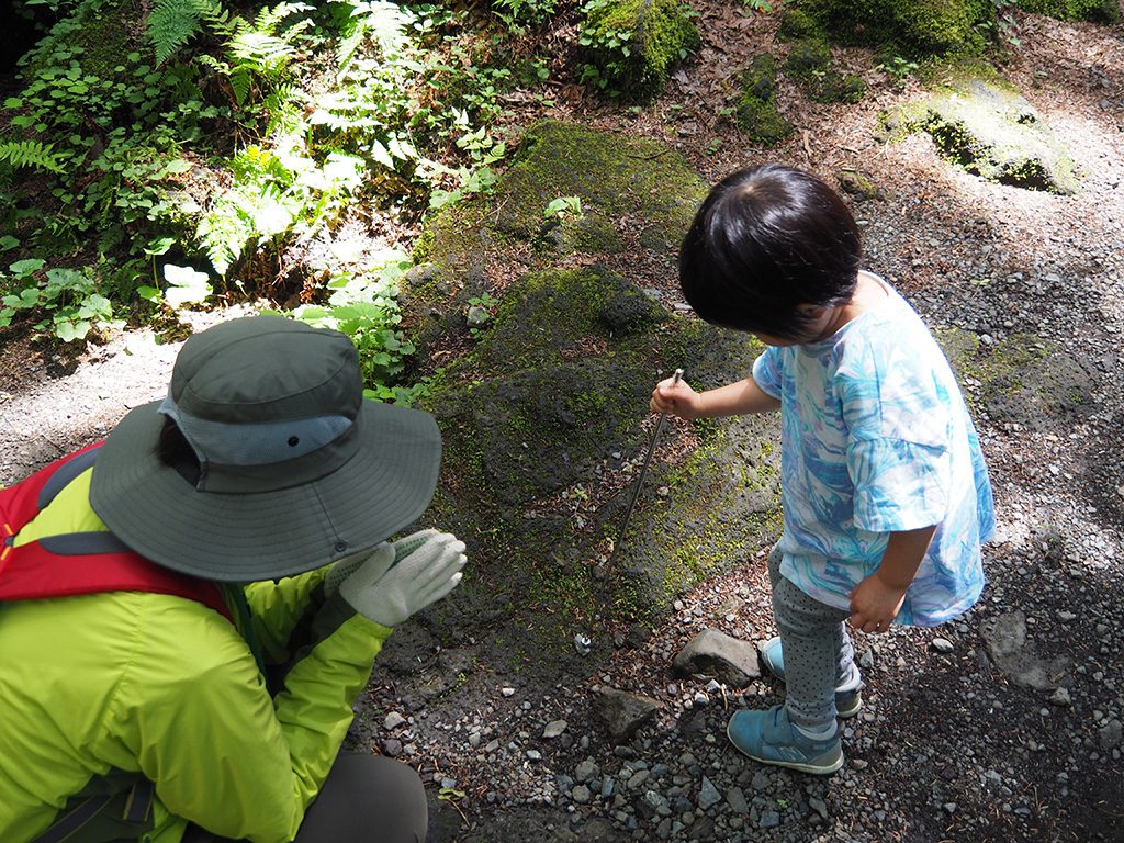 先に磁石がついた棒で石にふれる様子/洞窟「富岳風穴」(山梨県/富士河口湖町)