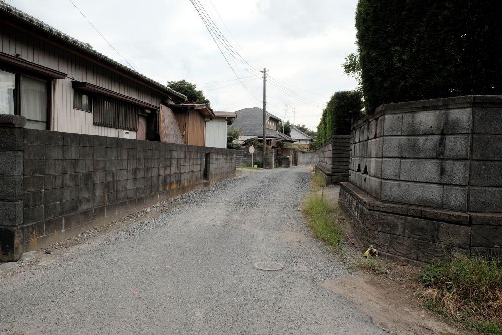 千葉県山武郡九十九里町粟生の売買物件/前面道路は砂利はR７年春に舗装予定。奥にある斜め屋根のお家が本物件。