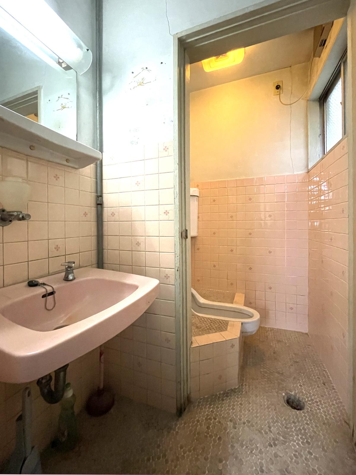 福岡県直方市古町の賃貸物件/薄ピンクの和式トイレと洗面台。