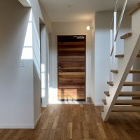 鎌倉市津の賃貸物件/1階 玄関｜板張りが特徴の扉を開けた先は、吹き抜けの空間と階段