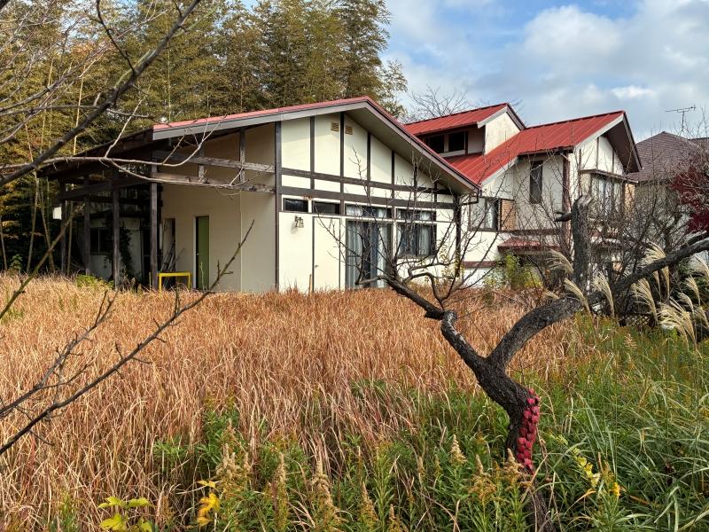 鎌倉市鎌倉山四丁目の売買物件/外部｜木々の間から見える家に向かって草をかき分けていくと、赤い切妻屋根が連なった面白い形の家が現れます