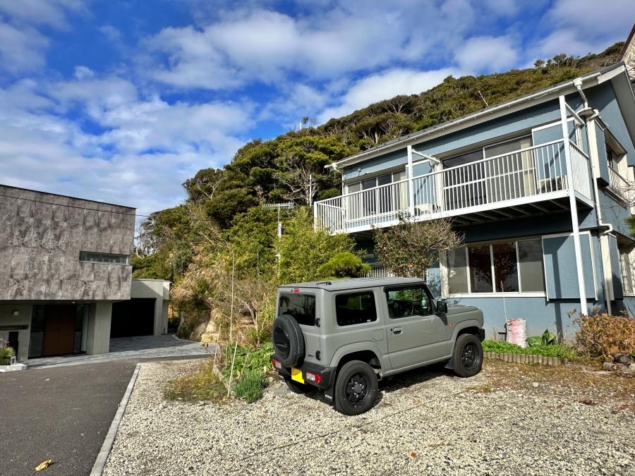 鎌倉市稲村ガ崎一丁目の賃貸物件/外観｜青い空に映える水色の外壁。手前には3台ほど駐車できるスペースがありますが、利用できるのは1区画のみ