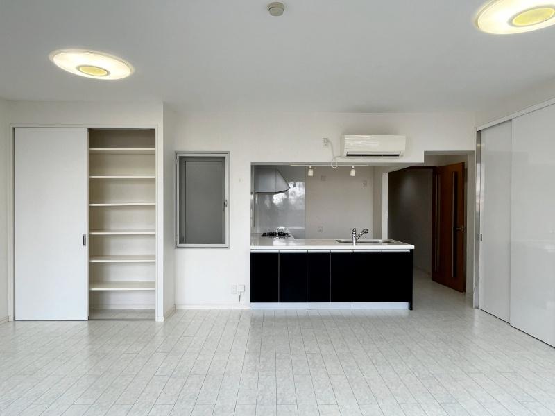 逗子市小坪五丁目の売買物件/LDK別角度│引き戸の収納棚が2つ、キッチン作業台の手前(黒い扉)も収納棚