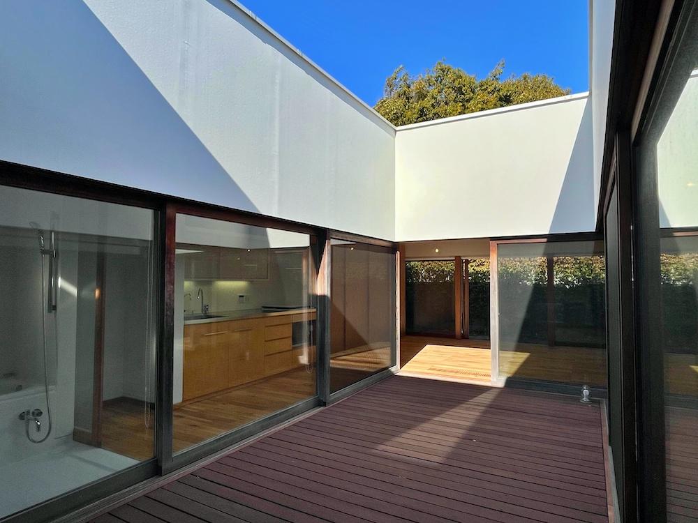 茅ヶ崎市東海岸南四丁目の売買物件/中庭｜青く切り取られた空、そこから奥のリビングへ光が注がれます。左側にキッチンやバスルームが並ぶ。