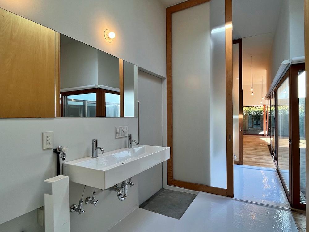 茅ヶ崎市東海岸南四丁目の売買物件/洗面室｜洗面台には水栓が2つ。そして鏡がワイドであることがうれしい。手前は洗濯機置き場。