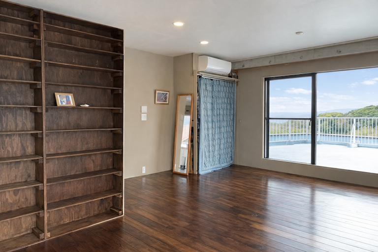 足柄下郡湯河原町吉浜の売買物件/北西側洋室は二部屋をつなげて約13.5帖。棚はオーナーがDIYで造作、塗装