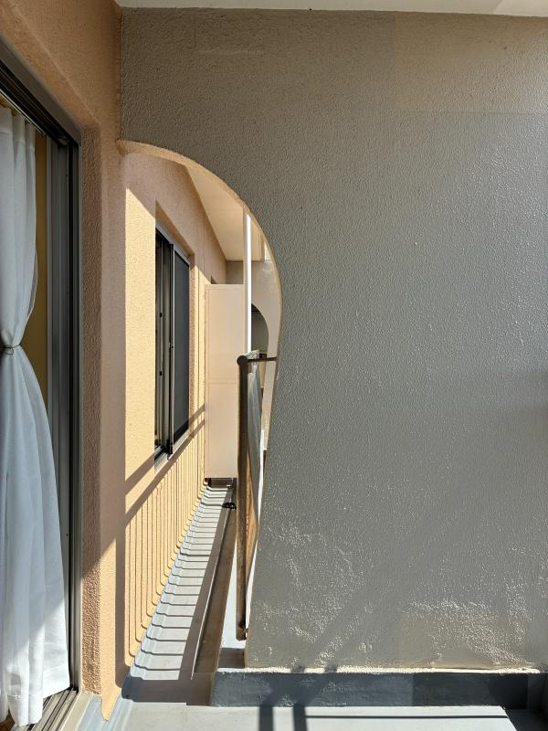 逗子市小坪二丁目の売買物件/バルコニーのアール壁がチャームポイント。クリーム色のやわらかな曲線を描いています。この壁のおかげで、奥の腰窓からも海が覗けるんです（写真1枚目）