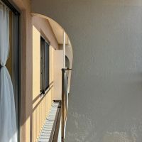 逗子市小坪二丁目の売買物件/バルコニーのアール壁がチャームポイント。クリーム色のやわらかな曲線を描いています。この壁のおかげで、奥の腰窓からも海が覗けるんです（写真1枚目）