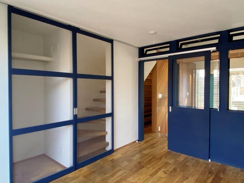 藤沢市本鵠沼四丁目の賃貸物件/1階洋室7帖│青で統一された建具。収納と階段の扉は、金網が使用されています