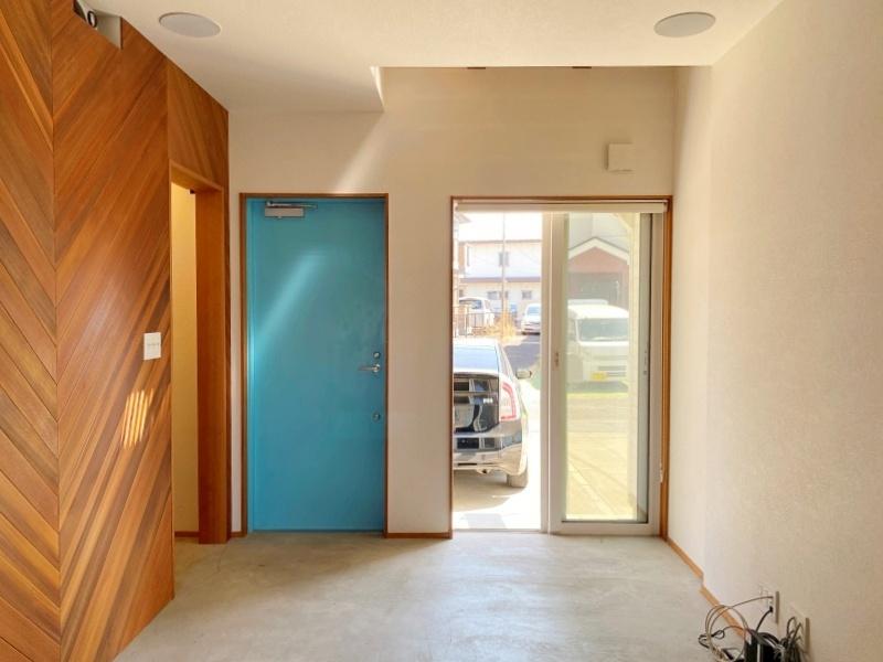 藤沢市本鵠沼四丁目の賃貸物件/1階土間リビング│水色の扉とヘリンボーンの壁がかわいい。写真左奥のスペースには、洗面台と靴収納