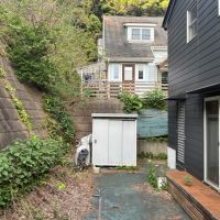 鎌倉市極楽寺三丁目の賃貸物件/建物裏｜山が迫っています。奥に見えるのは非賃貸の倉庫