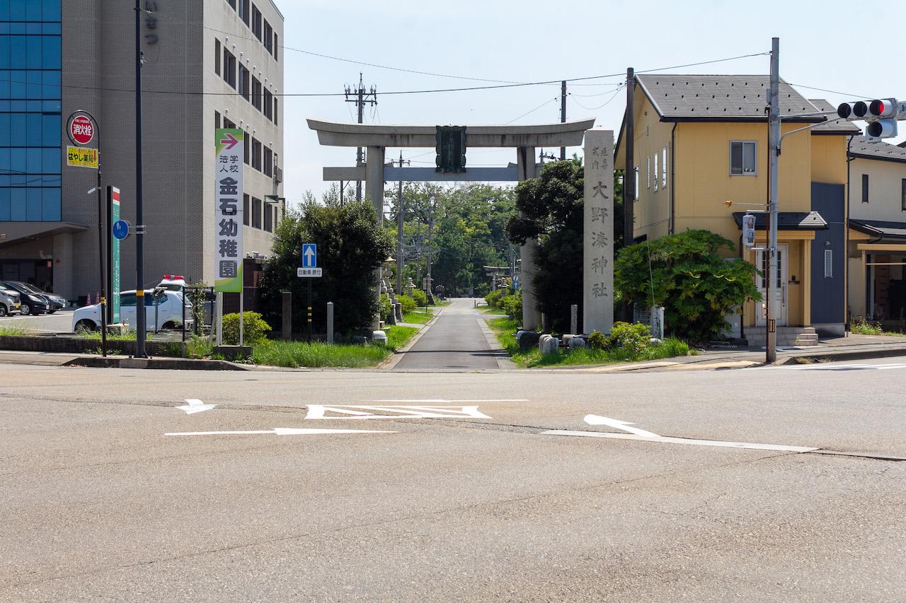 金沢市金石本町の売買物件/交差点にそびえ立つ大野湊神社の一の鳥居。その鳥居をくぐり表参道を進み、二の鳥居がある橋の手前で曲がった先に本物件があります。