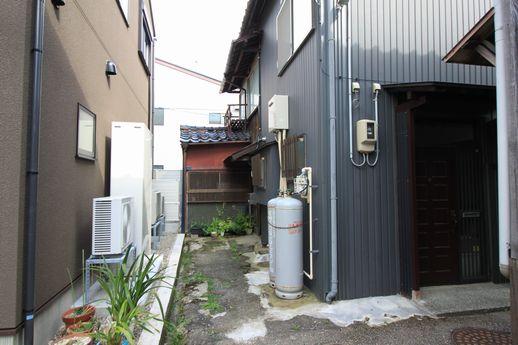 奥のドンつきが本物件玄関。お隣さんが外壁をグレーのガルバにしちゃいました。