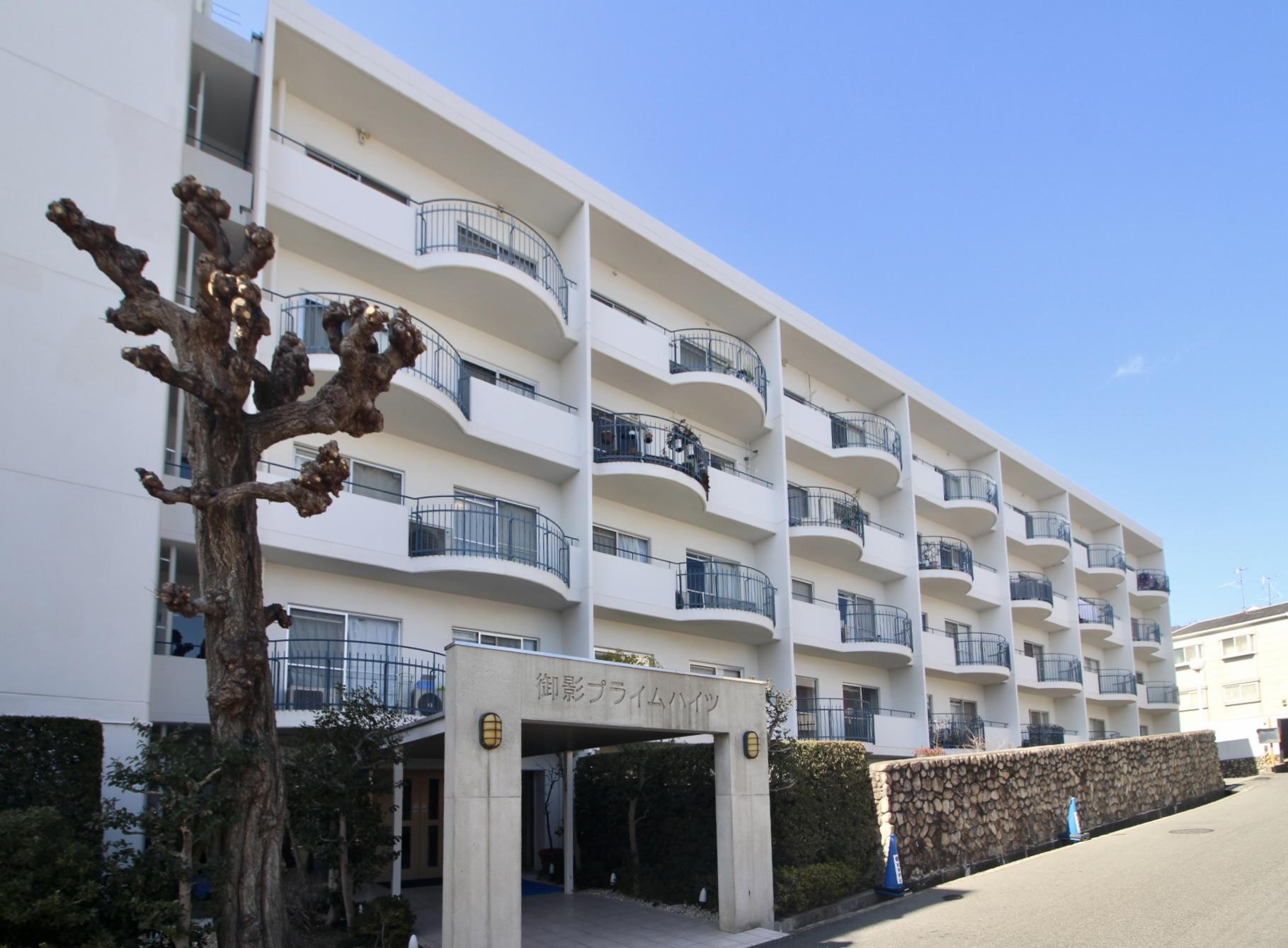 神戸市東灘区住吉山手の売買物件/白い外壁とアールのバルコニー、石垣と生垣。瀟洒なリゾートマンションのような佇まい。