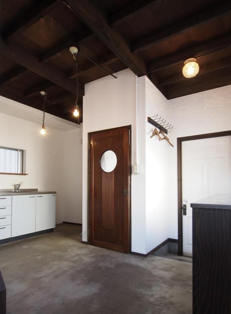 神戸市垂水区塩屋台の売買物件/コンクリートの土間床に、丸い開口の木製建具が印象的な、1階の玄関・キッチン空間。