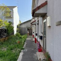 京都市北区紫野上柳町3の賃貸物件/手前の共同住宅に半分隠れるように建つ（草が生えてる空き地は他人地です）