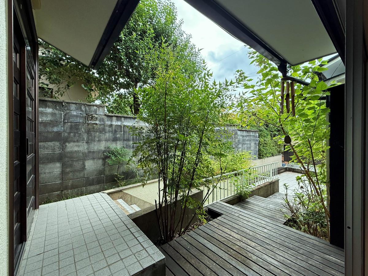 京都市左京区上高野西明寺山33ー10の売買物件/1階奥玄関外。階段降りると車庫、ウッドデッキを進むと車庫上のテラスにでます。合間にたくさん緑があるので森の中のような穏やかさ