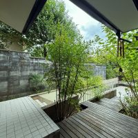京都市左京区上高野西明寺山33ー10の売買物件/1階奥玄関外。階段降りると車庫、ウッドデッキを進むと車庫上のテラスにでます。合間にたくさん緑があるので森の中のような穏やかさ