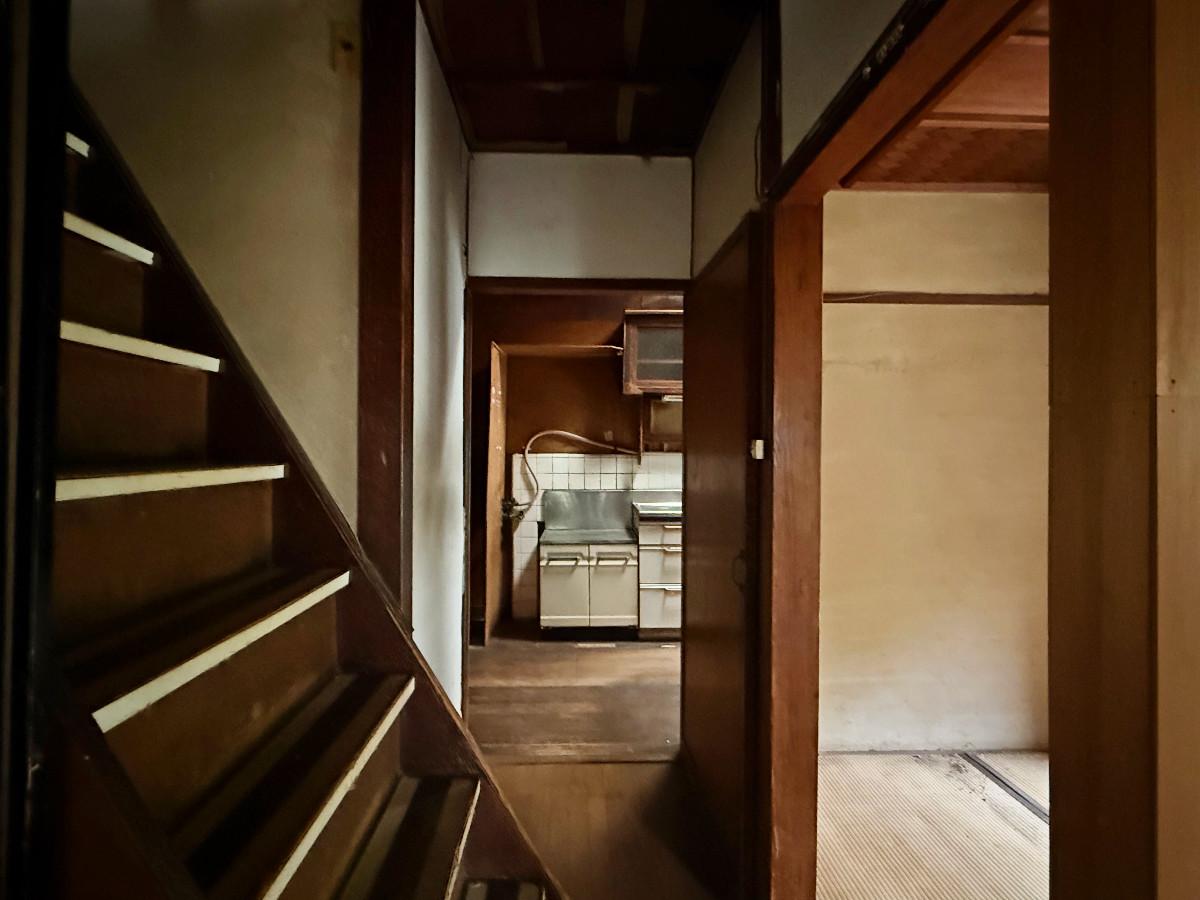 京都市山科区日ノ岡夷谷町21-9の売買物件/玄関間階段越しに台所。階段が廊下まで張り出していても急勾配。ここはちょっと手直ししたいところです
