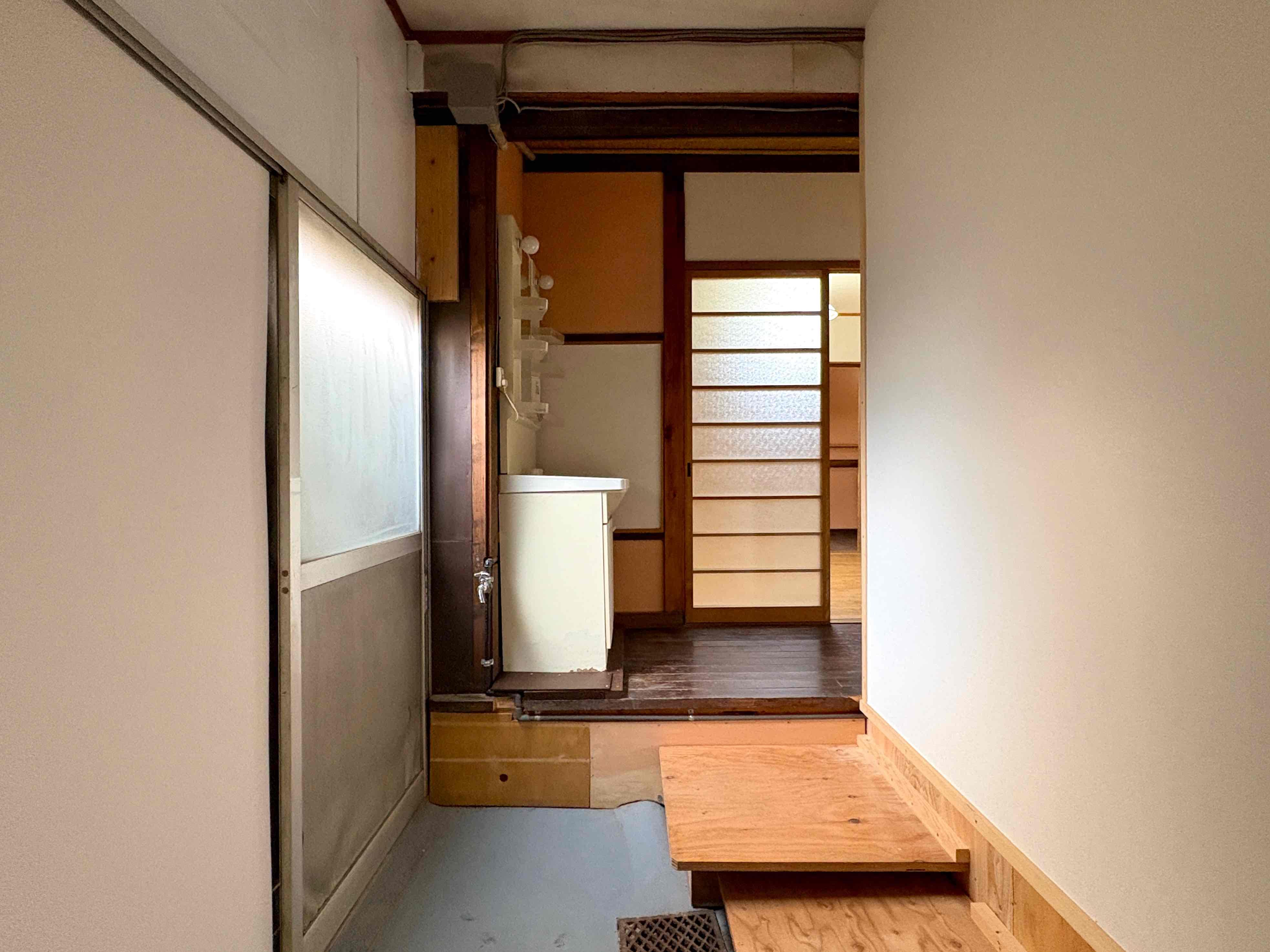 京都市北区紫竹上梅ノ木町2番地の賃貸物件/洗面横の土間に室内洗濯機置き場。左手の引き戸を開ければ目の前に塀が反り立つ