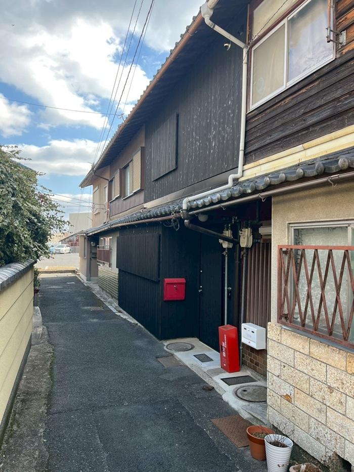 滋賀県大津市尾花川9-18の売買物件/該当物件は4連棟の真ん中。路地を抜けると近隣店舗の駐車場へ続いている。