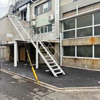 京都市下京区朱雀宝蔵町56の賃貸物件/外観。白い階段を上がって二階の引戸を開けると共用ラウンジにつながっています。2階左手に飛び出しているのが冷蔵室部分