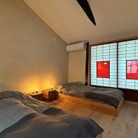 〒600-8141 京都府京都市下京区新日吉町１２４&minus;１０の賃貸物件/2階ベッドコーナー。町屋ですので、低めベッドでお布団風に。サイドテーブルにオリジナル照明がきらりと光ります。建具の赤もポップで日本人にはない感覚