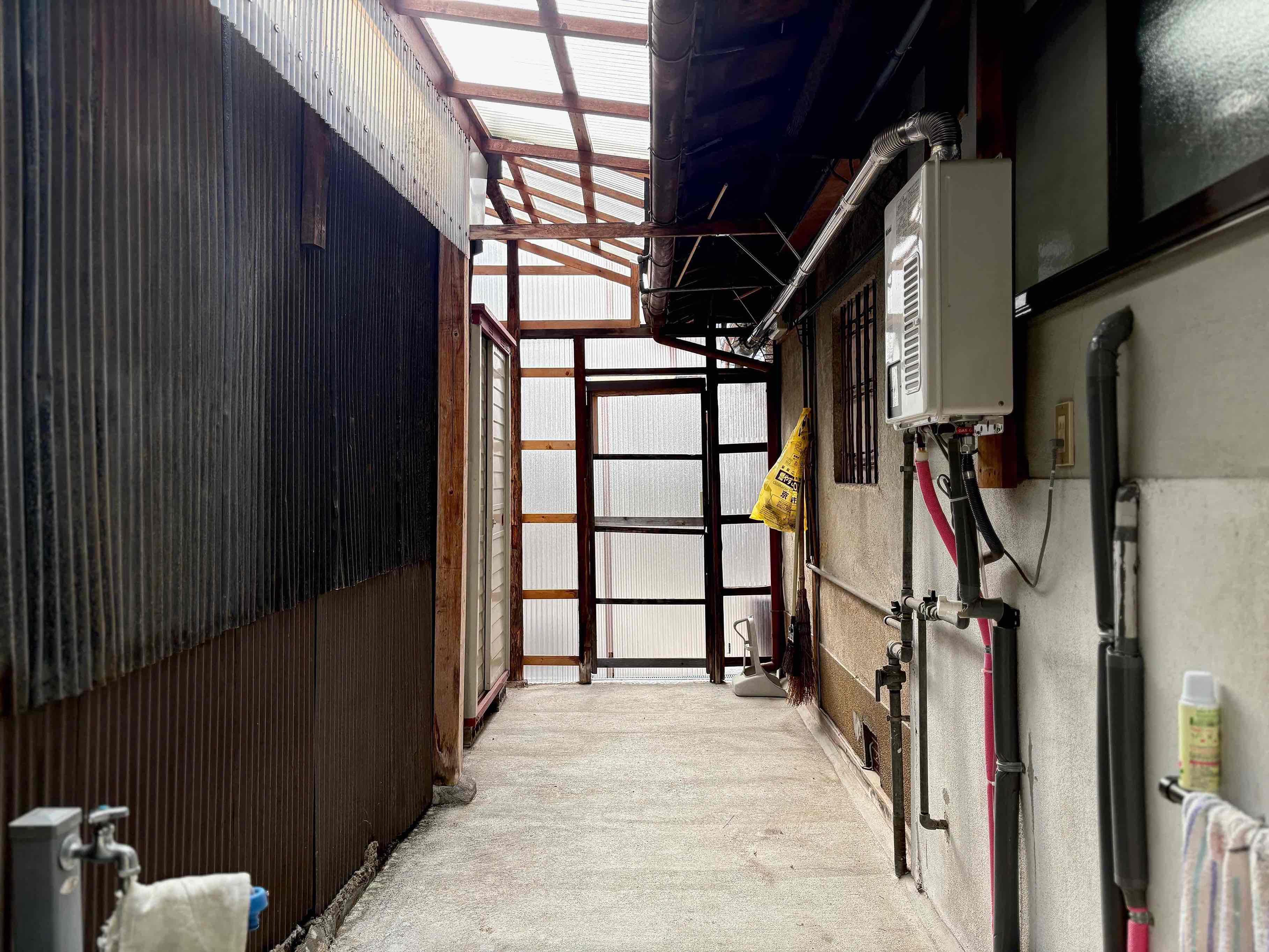 京都市北区紫野南舟岡町74-4の賃貸物件/玄関横の土間の様子。奥の扉がアプローチに続きます。手前に水道があって、屋根もあるので駐輪スペースにぴったりかも