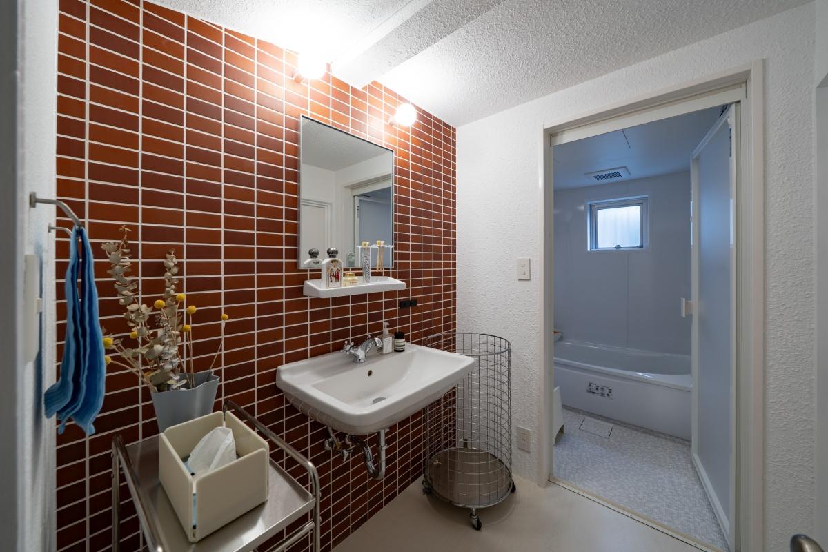 大阪府豊中市上新田の売買物件/レンガタイルの洗面台と奥にはユニットバス。