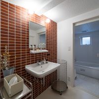 大阪府豊中市上新田の売買物件/レンガタイルの洗面台と奥にはユニットバス。