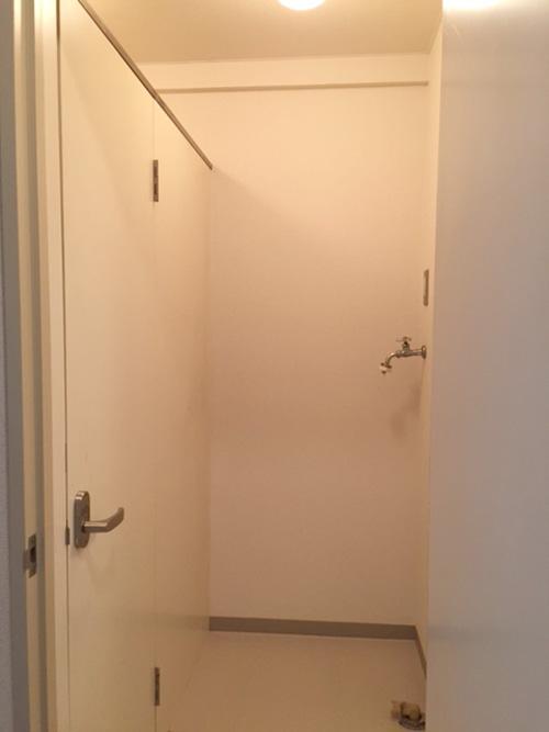 洗濯機置き場兼脱衣所。左側がトイレのドアで、上が開いているタイプ
