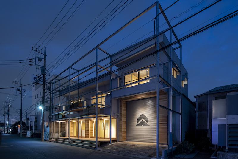 横浜市都筑区池辺町の賃貸物件/夜は照明で建物が浮かび上がります、シャッターにペイントされた桃と山の企業ロゴがライトアップされ目立っています