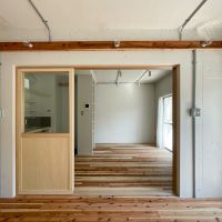 新宿区赤城下町の賃貸物件/西側の洋室からリビングを眺める。ガス管に収められた配線や、ステンレスのスイッチプレートが空間を引き締めている