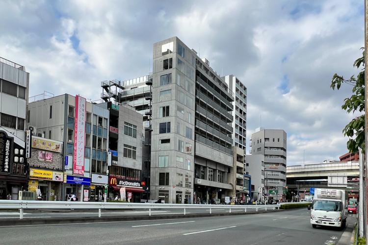 江東区門前仲町の賃貸物件/建物外観。中央の細長いコンクリート打ちっぱなしのビル
