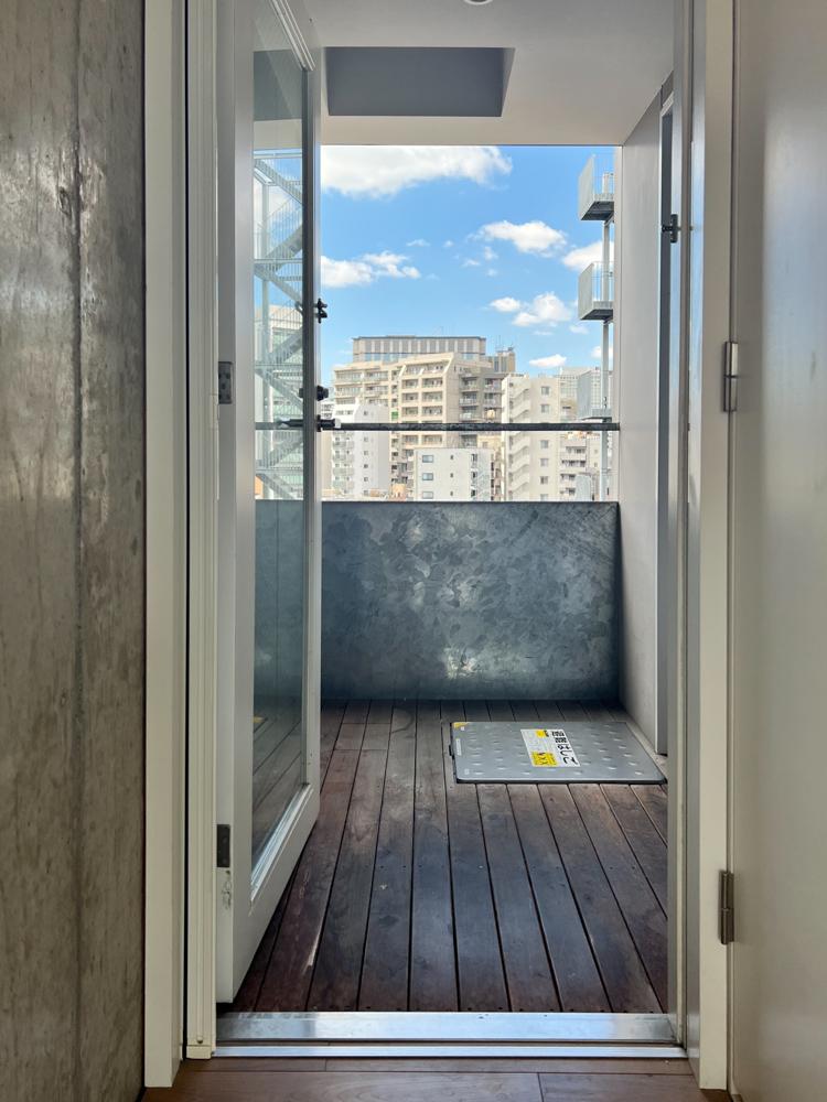 江東区門前仲町の賃貸物件/エレベーターから玄関までの屋外廊下はウッドデッキ。ベランダはありませんが、ワンフロア1住戸なので他の入居者さんはここに自転車など置いているようでした