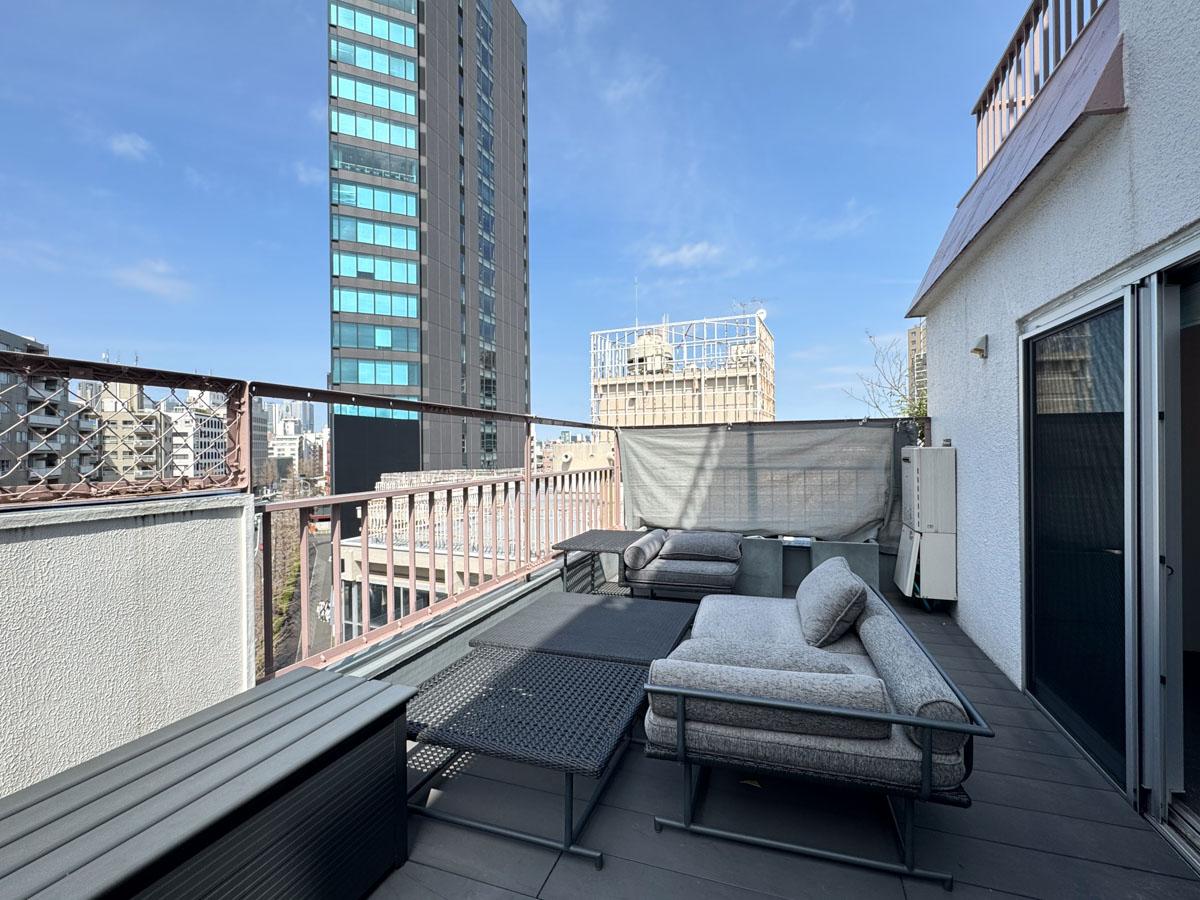 渋谷区神宮前の賃貸物件/ワイドなバルコニーには、オーナーが残したソファーやテーブル。原宿にいながら広い空が楽しめる、癒しの場所