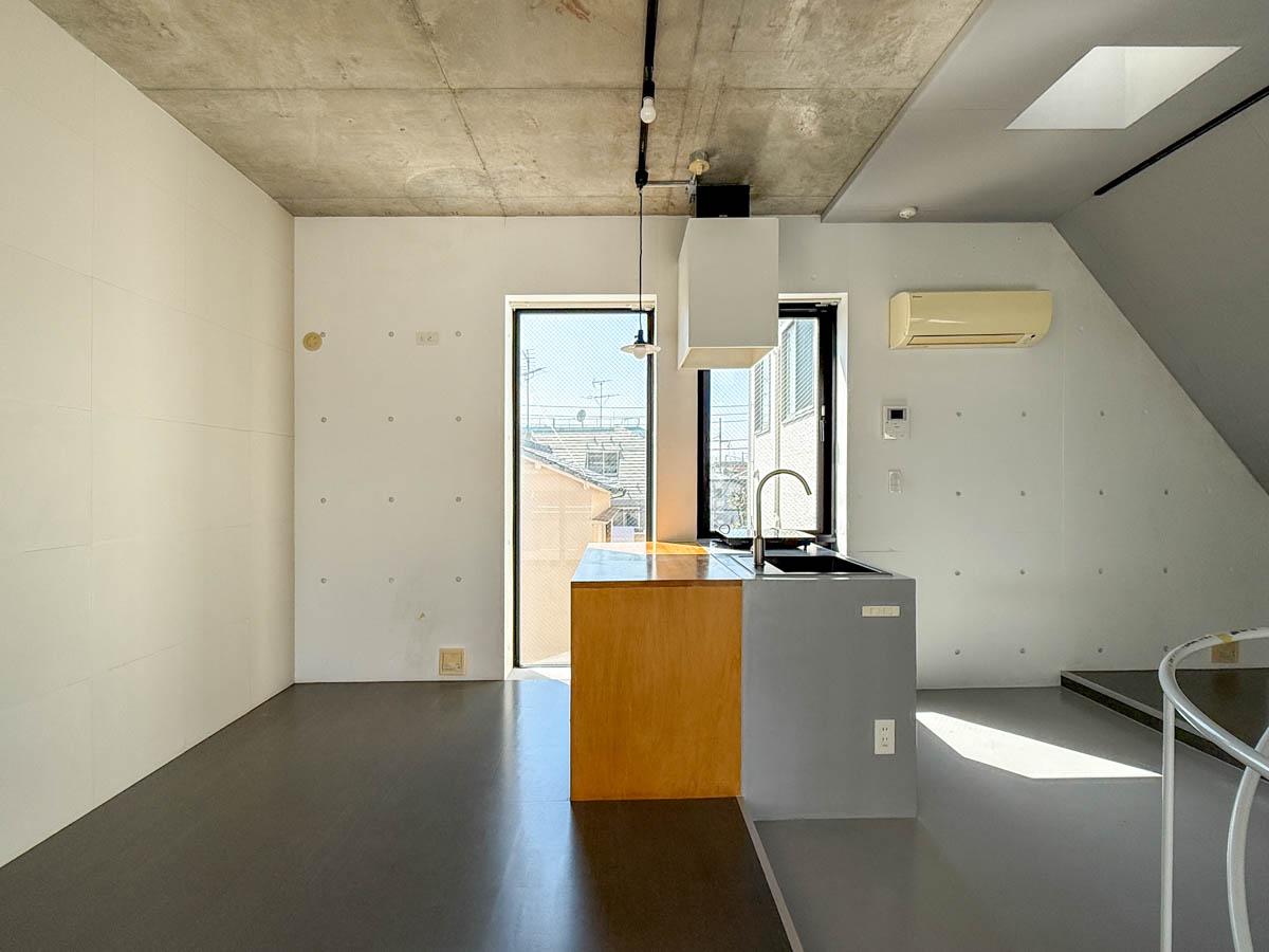 中野区南台の賃貸物件/キッチンに対面するように、木のテーブルが造作されている。西側の隣地は今は開けていますが、これから建物が建ちそう