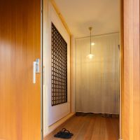所沢市下安松の売買物件/木製の玄関ドアをあけると、デッキ材のような木が敷かれ、温もりを感じる。引き戸は古い格子の建具をリメイクしたもの