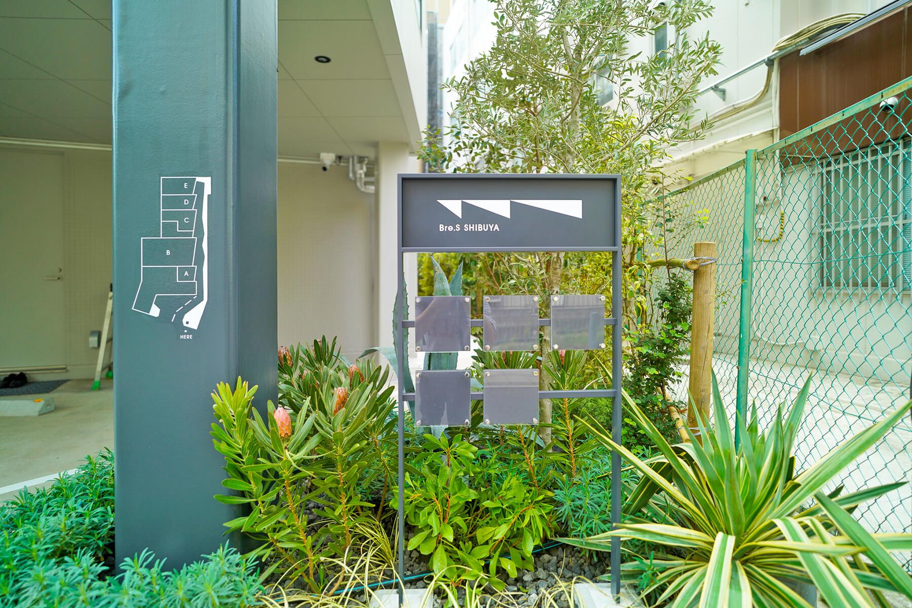 渋谷区渋谷の賃貸物件/建物前にある看板。植栽の雰囲気がいい感じ。1階の店舗は看板にお店のロゴ等を表現することが可能です