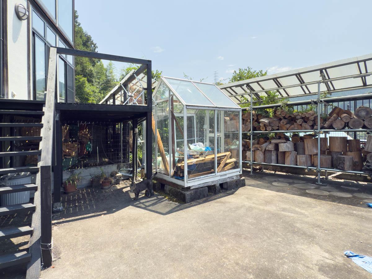 青梅市沢井の売買物件/ガラス製の温室や薪台が置かれたお庭