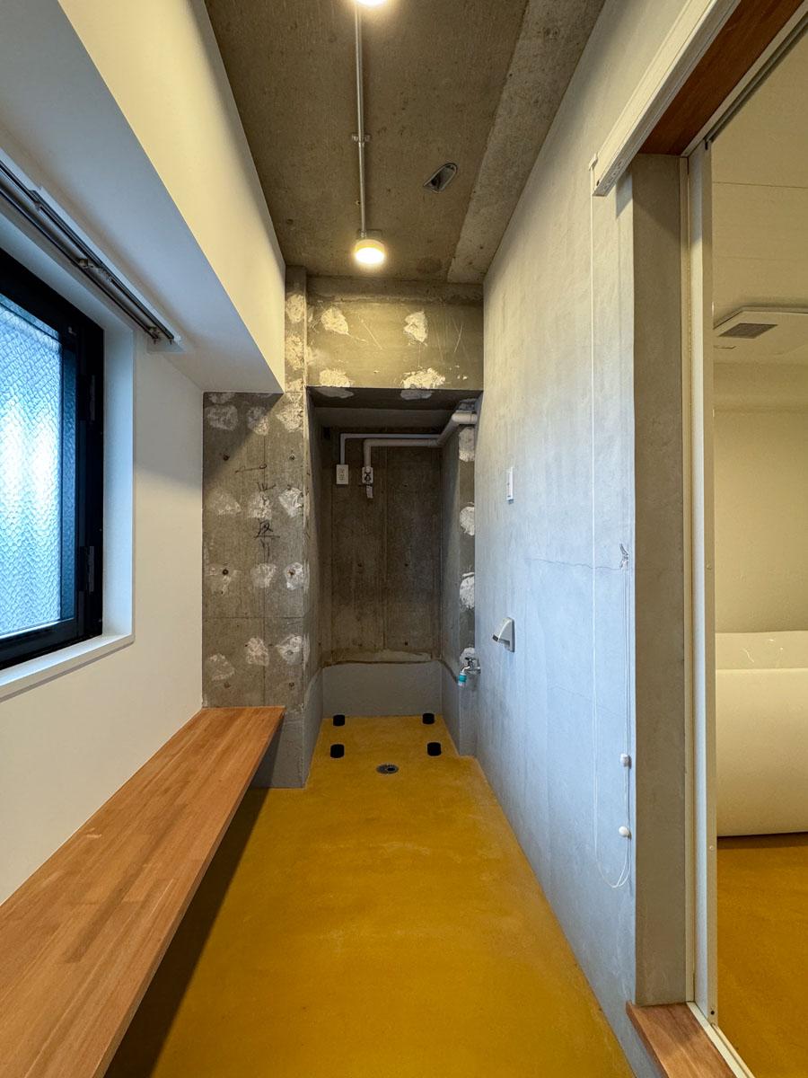 府中市天神町の賃貸物件/玄関を入ってすぐの土間（橙色に塗装されたモルタル）。一番奥に洗濯機置き場