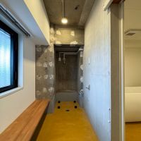 府中市天神町の賃貸物件/玄関を入ってすぐの土間（橙色に塗装されたモルタル）。一番奥に洗濯機置き場